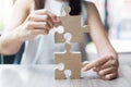 Woman hands connecting couple puzzle over table, businesswoman holding wood jigsaw inside office. Business solutions, mission, Royalty Free Stock Photo