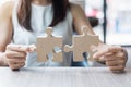 Woman hands connecting couple puzzle over table, businesswoman holding wood jigsaw inside office. Business solutions, mission, Royalty Free Stock Photo