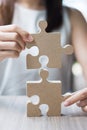 Woman hands connecting couple puzzle over table, businesswoman holding wood jigsaw inside office. Business solutions, mission, Royalty Free Stock Photo