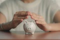 Woman hands covering piggy bank and saving money