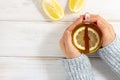 Woman hands in cozy sweater hold cup of tea with lemon on white wooden table Royalty Free Stock Photo