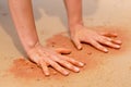 Woman hands creating shapes with red sand on the beach in aboriginal art style Royalty Free Stock Photo