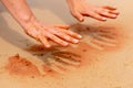 Woman hands creating shapes with red sand on the beach in aboriginal art style Royalty Free Stock Photo
