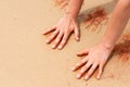Woman hands creating shapes with red sand on the beach in aboriginal art style Royalty Free Stock Photo