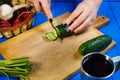 Woman hands cutting fresh crunchy cucumber on cutting board with Royalty Free Stock Photo