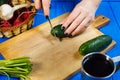 Woman hands cutting fresh crunchy cucumber on cutting board with Royalty Free Stock Photo