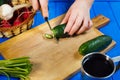 Woman hands cutting fresh crunchy cucumber on cutting board with Royalty Free Stock Photo