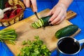 Woman hands cutting fresh crunchy cucumber on cutting board with Royalty Free Stock Photo