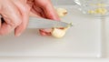 Woman hands cutting fresh garlic cloves on a white plastic container, close-up view Royalty Free Stock Photo