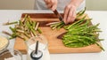 Woman hands cutting fresh green asparagus on wooden cutting board. Royalty Free Stock Photo