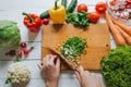 Woman hands cutting fresh green onion on wooden board overhead top view. White table background. Healthy cooking concept. Royalty Free Stock Photo