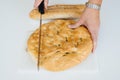 Woman hands cutting a loaf of bread on white table, food closeup Royalty Free Stock Photo