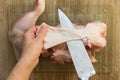 Woman hands cutting off skin from raw chicken leg with knife raw on glass cutting board on wooden background Royalty Free Stock Photo