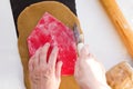 Woman hands cutting out with knife for pizza a wall of gingerbread house using homemade form for gingerbread house on rolled raw