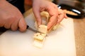 Woman hands cutting piece of cheese, she prepare food at kitchen. Chef cutting cheese with knife on wooden board. Royalty Free Stock Photo