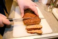 Woman hands cutting piece of meatloaf, she prepare for tasting of food at kitchen. Chef cutting meatloaf with knife on board. Royalty Free Stock Photo