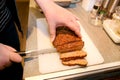 Woman hands cutting piece of meatloaf, she prepare for tasting of food at kitchen. Chef cutting meatloaf with knife on board. Royalty Free Stock Photo