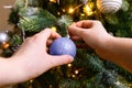 Woman hands decorating Christmas tree with ornaments ball colored in trendy color of year 2022 Very Peri background