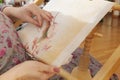 Woman hands doing cross-stitch embroidery on a linen cloth on an embroidery machine