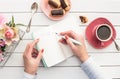 Woman hands drawing or writing with ink pen in open notebook on white wooden table. Royalty Free Stock Photo