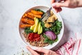 Woman hands eating vegan salad of baked vegetables, avocado, tofu and buckwheat buddha bowl, top view. Plant based food concept Royalty Free Stock Photo