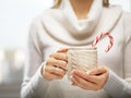 Woman hands with elegant french manicure nails design holding a cozy knitted mug with cocoa and a candy cane. Royalty Free Stock Photo