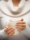 Woman hands with elegant french manicure nails design holding a cozy knitted mug. Winter and Christmas concept.