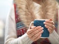 Woman hands with elegant french manicure nails design holding a cozy knitted mug. Winter and Christmas time concept.