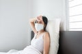 Woman hands on forehead and have a headache using protective mask with cold blowing and runny nose,Sick female sneezing on bed aft
