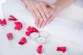 Woman hands with french manicure modern style on towel with red rose petals and candle in beauty salon Royalty Free Stock Photo