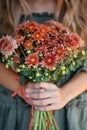 A woman hands gently hold a vibrant bouquet of chrysanthemums