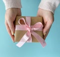 Woman hands give handmade present wrapped in craft paper with soft pink ribbon Royalty Free Stock Photo