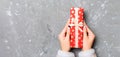 Woman hands give wrapped christmas or other holiday handmade present in colored paper . Present box, decoration of gift on gray Royalty Free Stock Photo