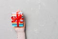 Woman hands give wrapped christmas or other holiday handmade present in colored paper . Present box, decoration of gift on gray Royalty Free Stock Photo