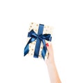 Woman hands give wrapped Christmas or other holiday handmade present in gold paper with blue ribbon. Isolated on white background Royalty Free Stock Photo