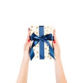 Woman hands give wrapped Christmas or other holiday handmade present in gold paper with blue ribbon. Isolated on white background Royalty Free Stock Photo