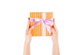 Woman hands give wrapped Christmas or other holiday handmade present in orange paper with purple ribbon. Isolated on white Royalty Free Stock Photo