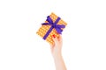 Woman hands give wrapped Christmas or other holiday handmade present in orange paper with purple ribbon. Isolated on white Royalty Free Stock Photo