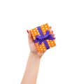 Woman hands give wrapped Christmas or other holiday handmade present in orange paper with purple ribbon. Isolated on white Royalty Free Stock Photo
