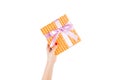 Woman hands give wrapped Christmas or other holiday handmade present in orange paper with purple ribbon. Isolated on white Royalty Free Stock Photo