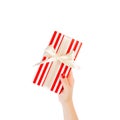 Woman hands give wrapped Christmas or other holiday handmade present in red paper with gold ribbon. Isolated on white background, Royalty Free Stock Photo