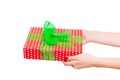 Woman hands give wrapped Christmas or other holiday handmade present in red paper with Green ribbon. Isolated on white background Royalty Free Stock Photo