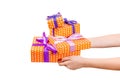 Woman hands give wrapped set of Christmas or other holiday handmade present in orange paper with purple ribbon. Isolated on white Royalty Free Stock Photo