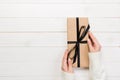 Woman hands give wrapped valentine or other holiday handmade present in paper with black ribbon. Present box, decoration of gift o Royalty Free Stock Photo