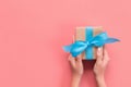 Woman hands give wrapped valentine or other holiday handmade present in paper with blue ribbon. Present box, decoration of gift on Royalty Free Stock Photo