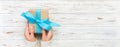 Woman hands give wrapped valentine or other holiday handmade present in paper with blue ribbon. Present box, decoration of gift on Royalty Free Stock Photo