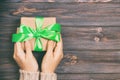 Woman hands give wrapped valentine or other holiday handmade present in paper with green ribbon. Present box, decoration of gift Royalty Free Stock Photo