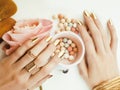 Woman hands with golden manicure and many rings holding brushes, makeup artist stuff stylish, pure close up pink Royalty Free Stock Photo