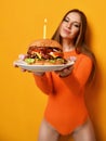 Woman hands hold big burger barbeque sandwich with beef and lit candle for birthday party on yellow Royalty Free Stock Photo