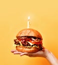 Woman hands hold big tasty burger barbeque sandwich with marble beef and lit candle for birthday party Royalty Free Stock Photo